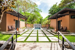 Une terrasse extérieure moderne avec une piscine, deux chaises longues et un mur en pierre.