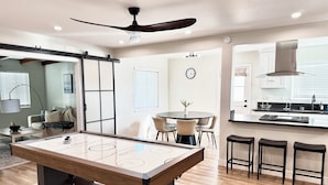 A modern kitchen with a central island, bar stools, and a dining area with chairs.