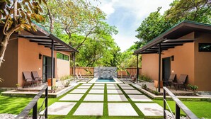 A pool area with a geometric tile pattern, two lounge chairs, and a stone wall in the center. - Private Tropical Compound • Exclusive Pool • 2 Villas • Fast WiFi (Provincia de Guanacaste)