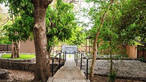 A paved pathway leading to a building with a stone wall and a wooden fence. - Private Tropical Compound • Exclusive Pool • 2 Villas • Fast WiFi (Provincia de Guanacaste)