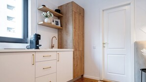 A kitchen with white cabinets, a wooden cabinet, and a window.