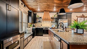 Una cocina moderna con armarios oscuros, encimeras de granito y una isla central.