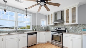 A modern kitchen with white cabinets, a stainless steel stove, and a dishwasher.