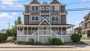 A two-story house with a porch, a small balcony, and a fish-shaped decoration above the entrance.