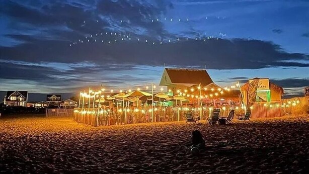 A beachside resort with string lights and a thatched-roof building.
