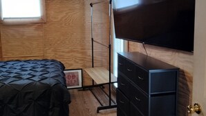 A bedroom with a bed, a dresser, a TV, and a window. - 1-bedroom apartment in the rear suite of the Howard Finster Vision House Museum. (Summerville)