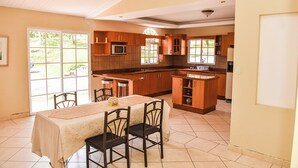 A spacious kitchen with a dining area, large windows, and a view of the outdoors. - Forest Villa near Zamorano & Uyuca Reserve (Tatumbla)