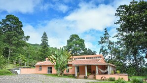 A two-story house with a tiled roof, surrounded by lush greenery and trees. - Forest Villa near Zamorano & Uyuca Reserve (Tatumbla)