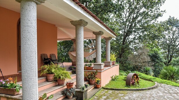 A covered porch with stone columns, potted plants, and outdoor seating. - Forest Villa near Zamorano & Uyuca Reserve (Tatumbla)