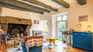 A cozy living room with a fireplace, wooden beams, a blue cabinet, and a view through a glass door. - Maison de Langonnet by Interhome (Langonnet)
