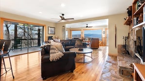 A spacious living room with a large window, a fireplace, and a stone accent wall.