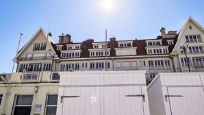 A beachfront hotel with multiple stories, balconies, and a sandy beach in the foreground.