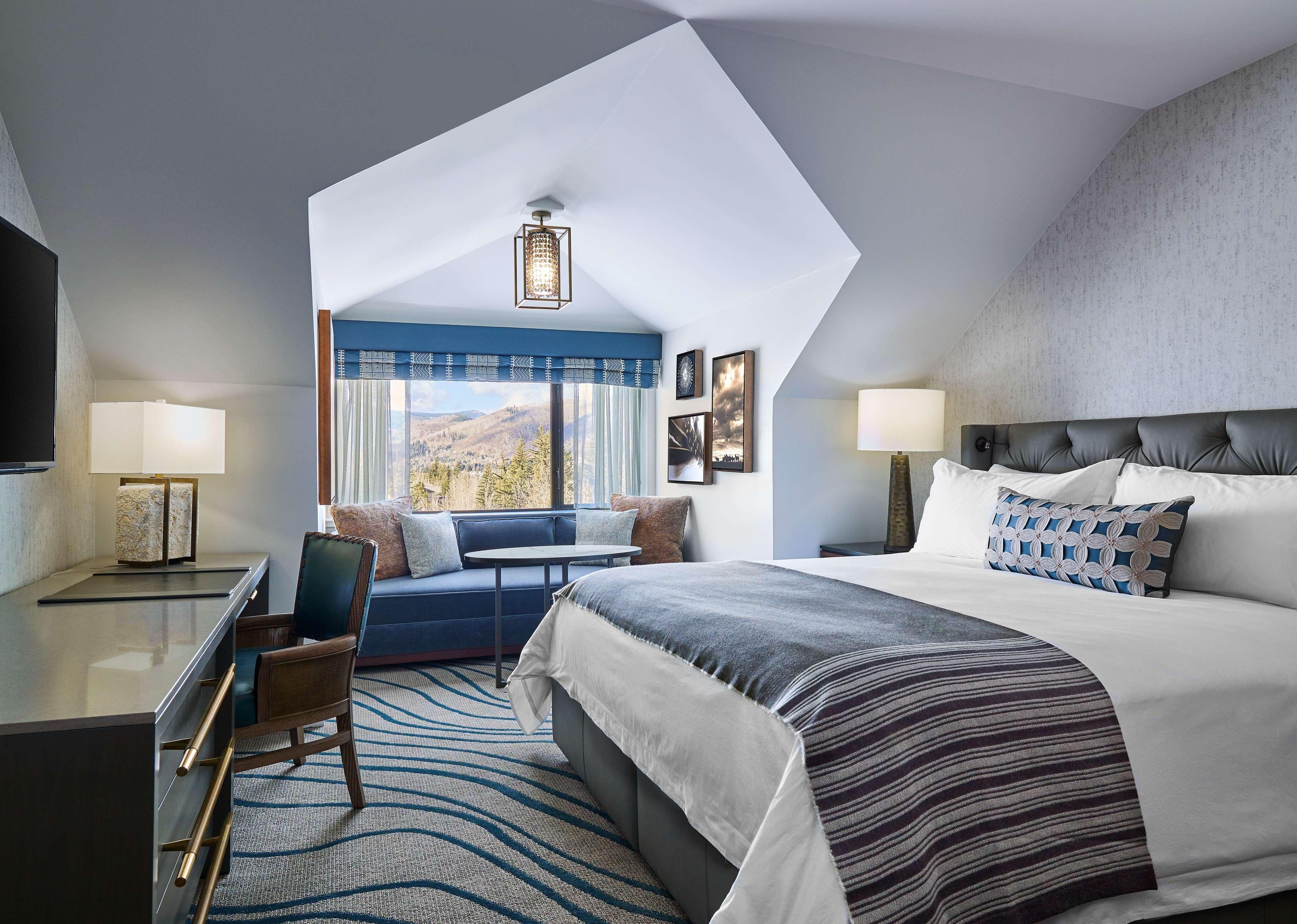 Une chambre d’hôtel moderne dotée d’un grand lit, d’un coin salon avec vue et d’une télévision.