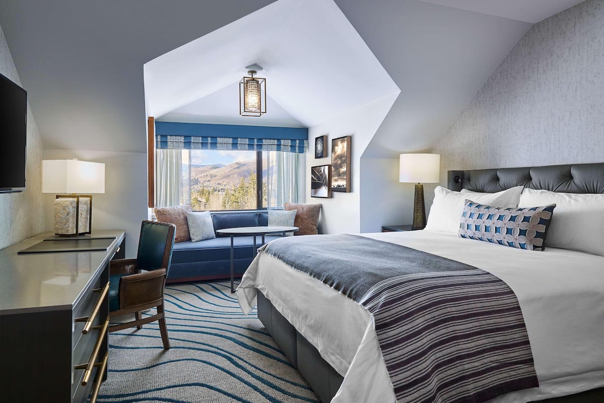 Une chambre d’hôtel moderne dotée d’un grand lit, d’un coin salon avec vue et d’une télévision.