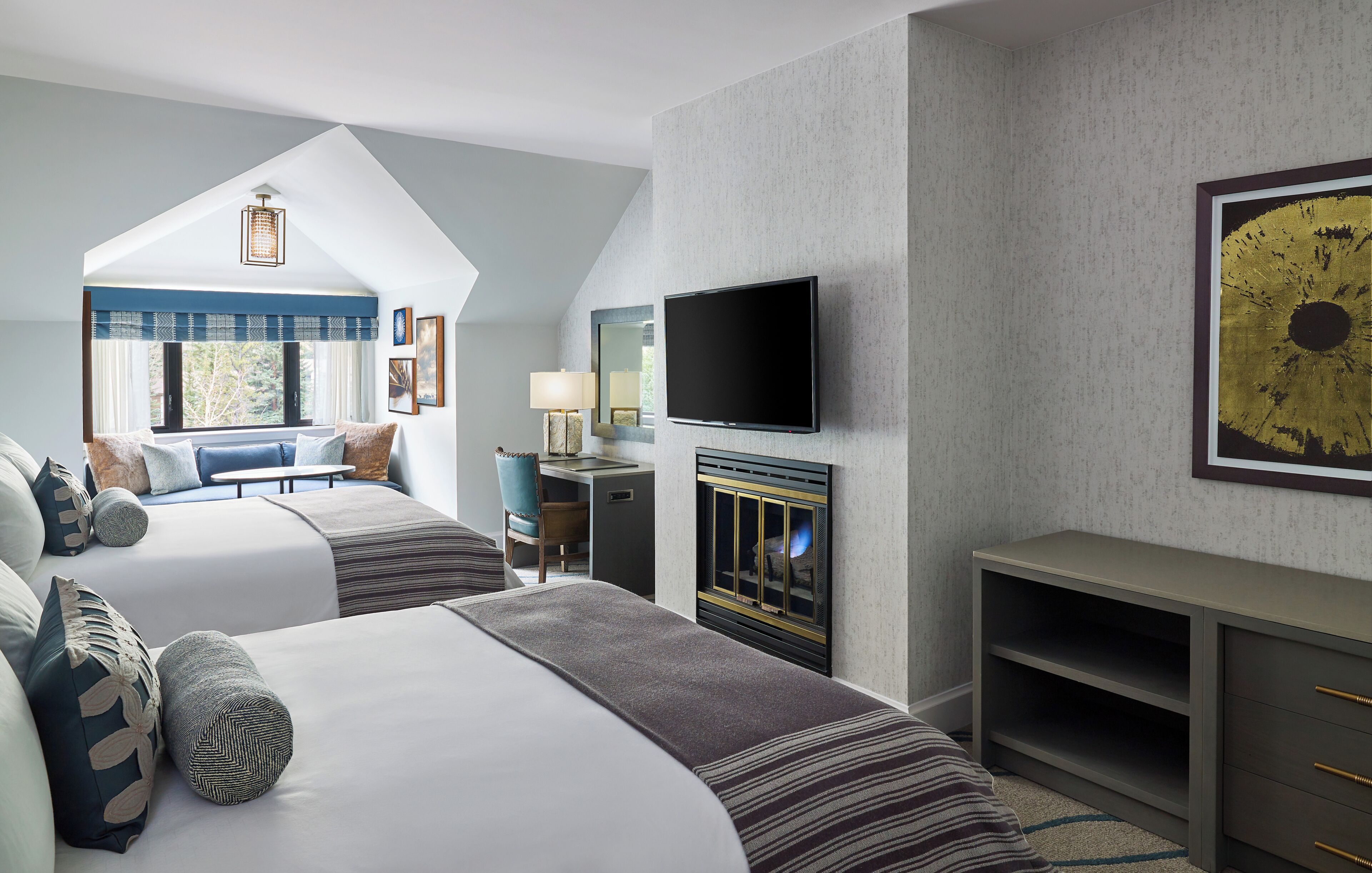 Une chambre d’hôtel avec deux lits, une télévision, une cheminée et un bureau.