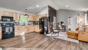 A modern kitchen with wooden cabinets, a black refrigerator, and a built-in oven.