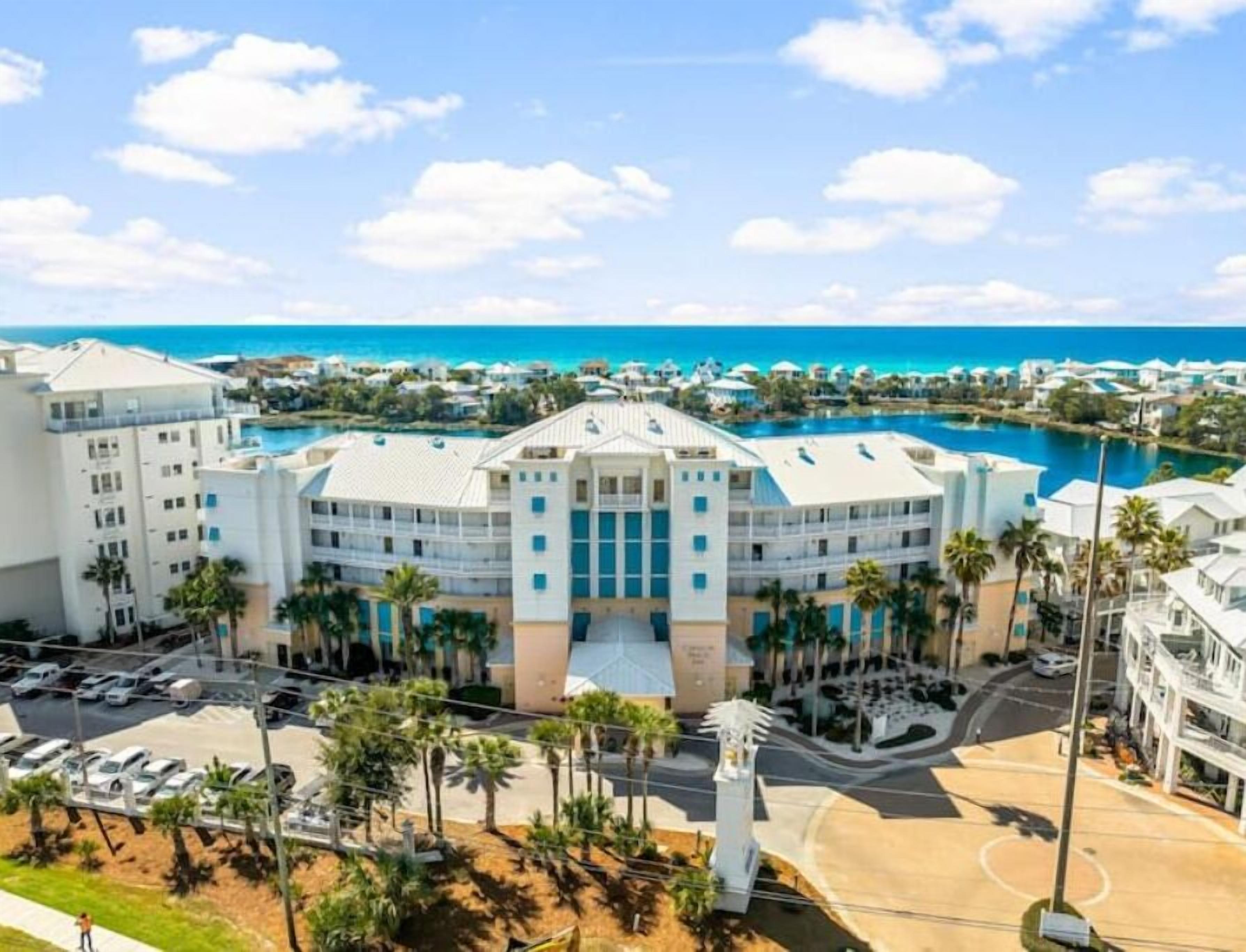 A large hotel with a central courtyard, multiple floors, and a view of the ocean.