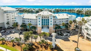 A large hotel with a central courtyard, multiple floors, and a view of the ocean. - 30a Luxury Condo, 3 private balconies, 4 Pools, 2 Hot Tubs, 5 min Walk to Beach! (Panama City Beach)