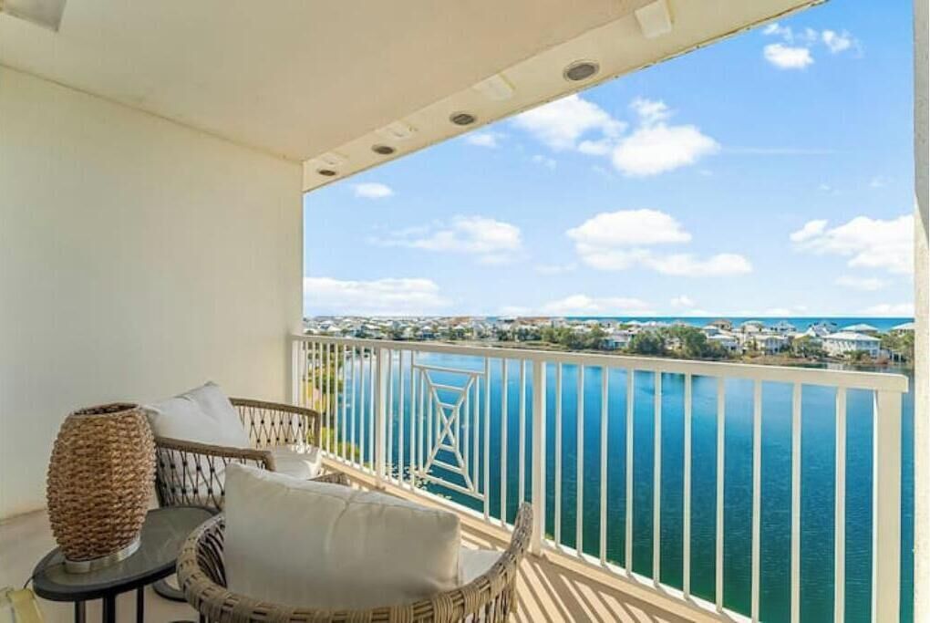 Un balcón con muebles de mimbre, vista al mar y barandilla.