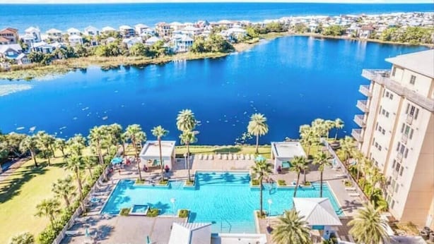 Et resort med en stor swimmingpool, palmer og havudsigt.