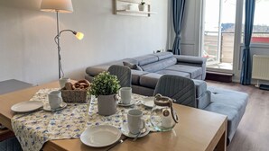 Un comedor con una mesa para dos personas, un sofá, una lámpara y vistas al exterior.