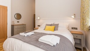 Een slaapkamer met een bed, nachtkastjes, een spiegel en een nachtkastje.