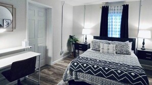A bedroom with a bed, a desk, and a chair.