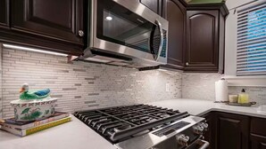 Una cocina moderna con armarios de madera oscura, estufa de acero inoxidable y microondas.