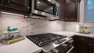A modern kitchen with dark wood cabinets, a stainless steel stove, and a microwave.