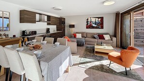 A modern living room with a dining area, a sofa set, and a kitchen.