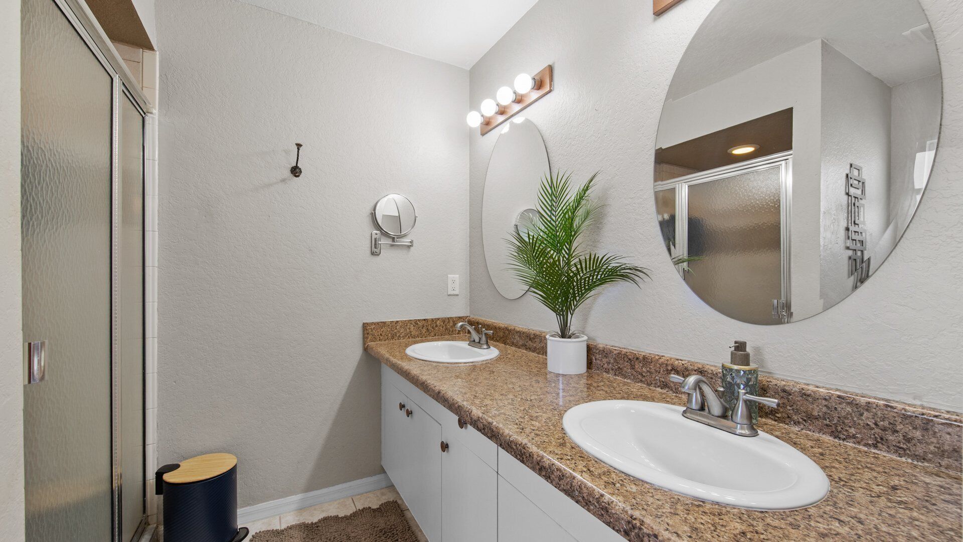 Une salle de bain avec deux lavabos, un grand miroir et des luminaires au-dessus du meuble-lavabo.