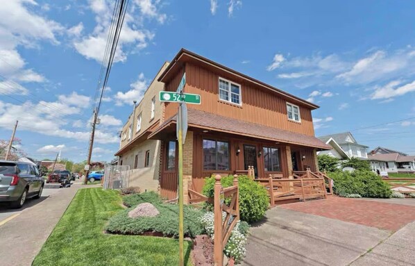 A two-story building with a front porch, a visible street sign, and a well-maintained lawn.