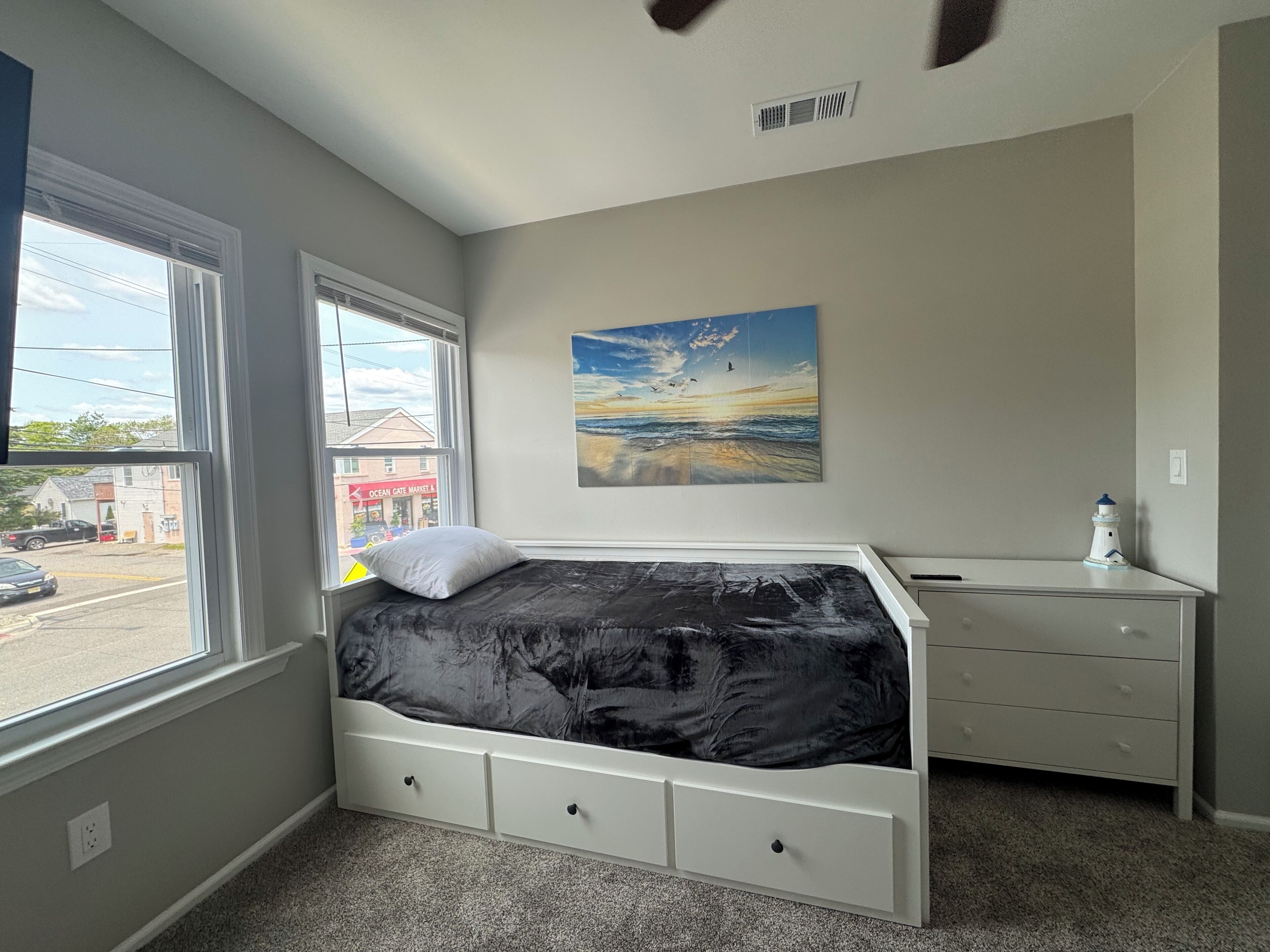 Une chambre à coucher avec un lit, une commode, une fenêtre et un tableau.