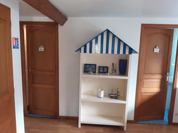 A room with wooden doors, a white shelf with decorative items, and a blue and white striped roof structure. - Le Manoir de Conteville (Paluel)