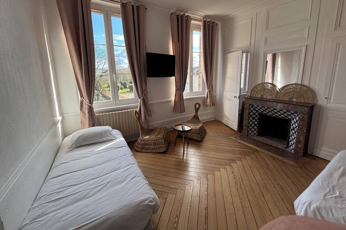 Une pièce comprenant un lit, une petite table, une chaise en osier, une cheminée et un téléviseur.
