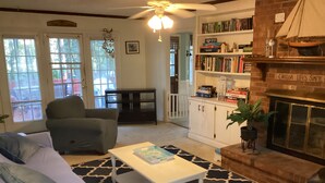 Una sala de estar acogedora con un sofá, una mesita de centro, una chimenea y una estantería llena de libros.