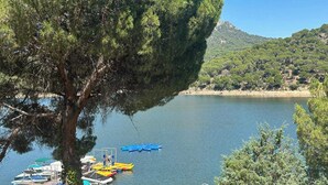 Un lac où sont amarrés des bateaux, entouré d’arbres et avec une montagne en arrière-plan.