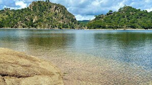 On peut clairement voir une plage de galets et un lac paisible.