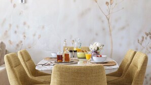 Comedor con una mesa redonda preparada para dos personas, con sillas de diseño tejido.