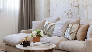 Una sala de estar con un sofá color beige, una mesa de centro redonda y un florero con flores.