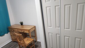 Un bureau en bois avec des tiroirs et une chaise, une plante en pot et une porte blanche à panneaux.