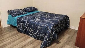 Ein Schlafzimmer mit einem Bett, einem Bild an der Wand und einem Holzboden.