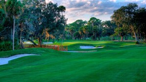 Un campo de golf con búnkeres de arena, un puente de madera y árboles densos.