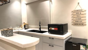 A compact kitchen with a microwave, sink, and refrigerator. - EWA Host (Riyadh)