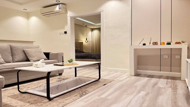 A modern living room with a sofa, coffee table, and a cabinet. - EWA Host (Riyadh)