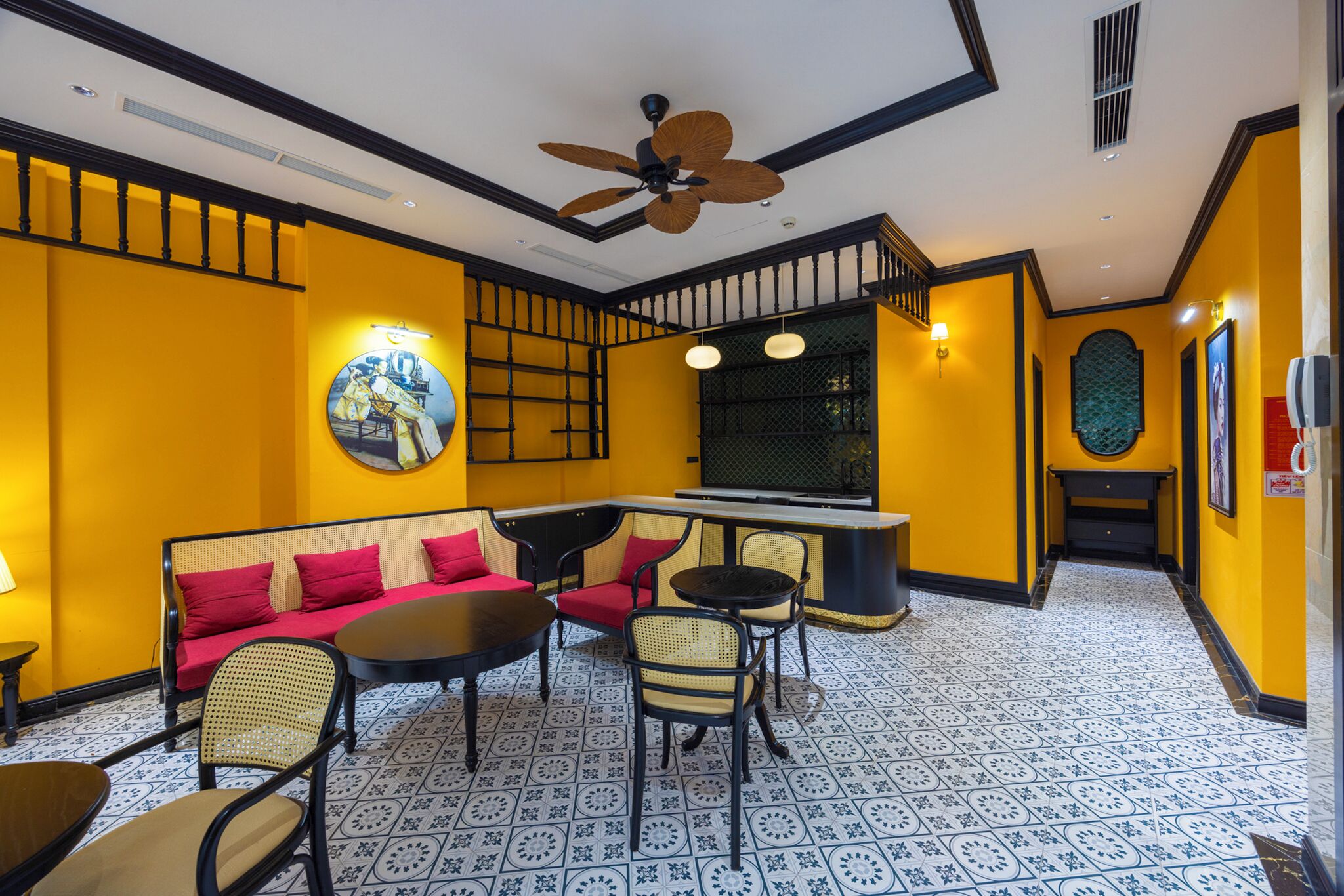 A room with a yellow wall, a ceiling fan, a round mirror, and a dining area with a table and chairs.