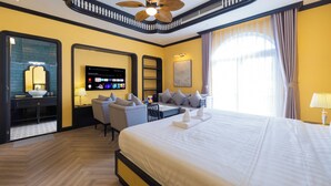 A hotel room with a large bed, a TV mounted on the wall, a desk with a chair, and a balcony with curtains. - Lotus Home Cafe - Signature (Phu Quoc)