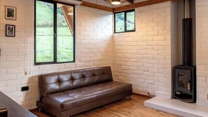Una habitación acogedora con techo de madera, un sofá, una mesa y una chimenea.
