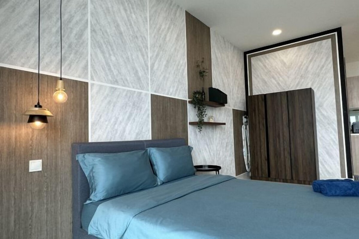 A modern bedroom with a bed, a hanging light fixture, and a wooden accent wall.