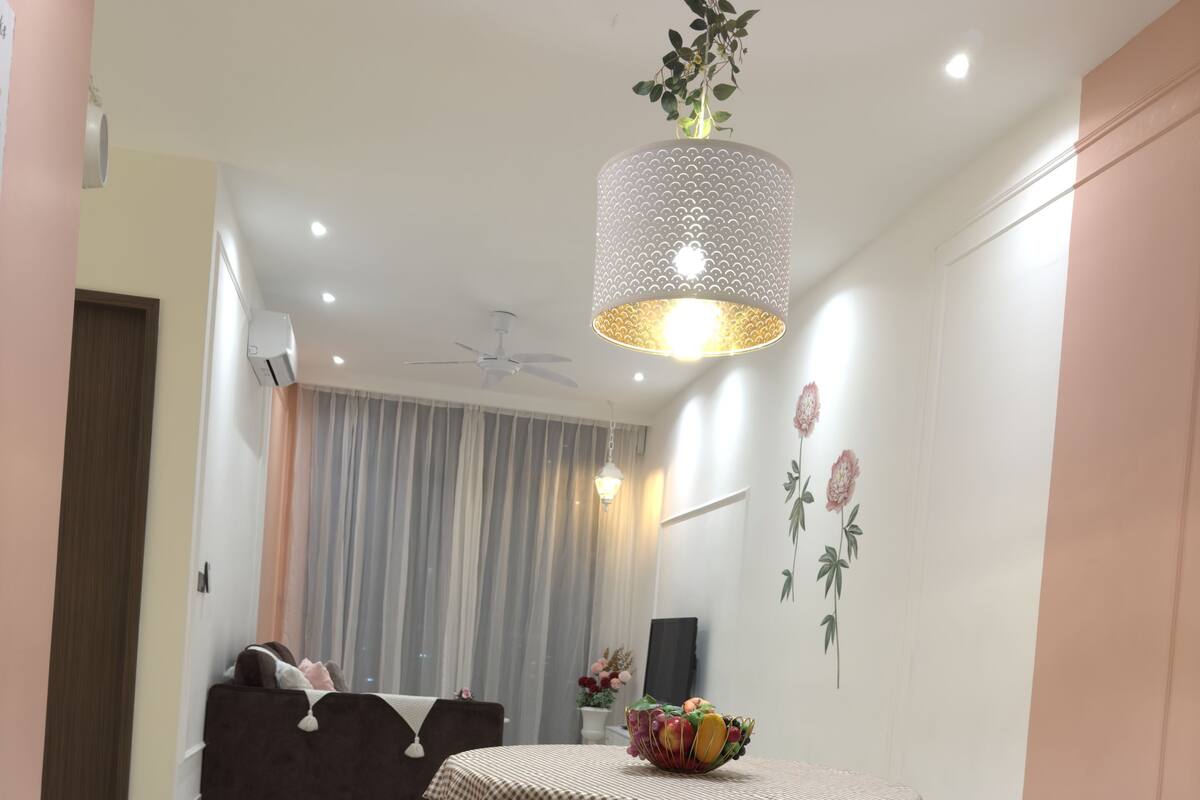 A dining area with a checkered tablecloth, four stools, a chandelier, and a wall with floral decorations.